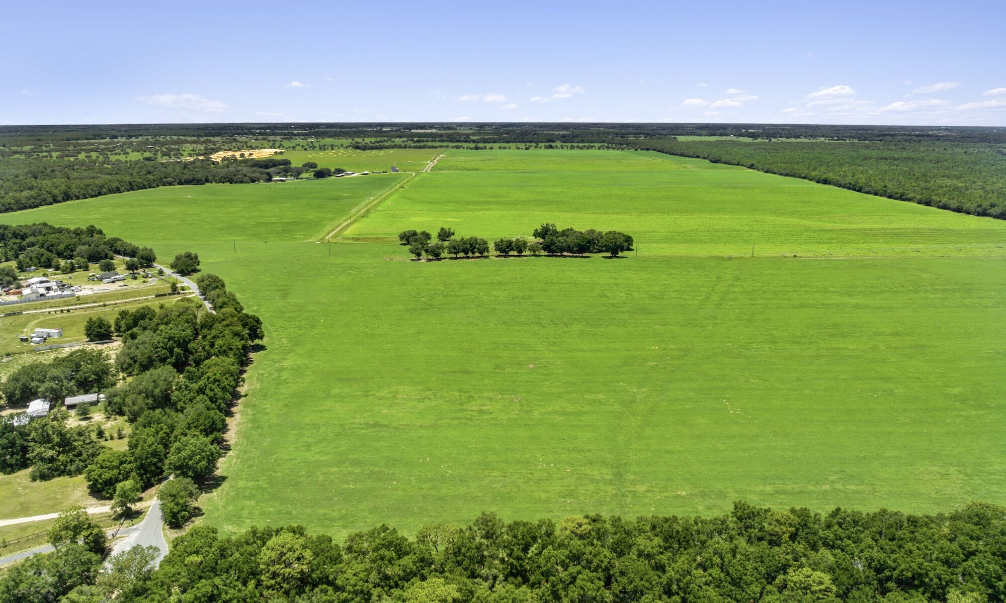 Land commercial real estate aerial photography showing acreage, access points, boundaries, and surrounding development