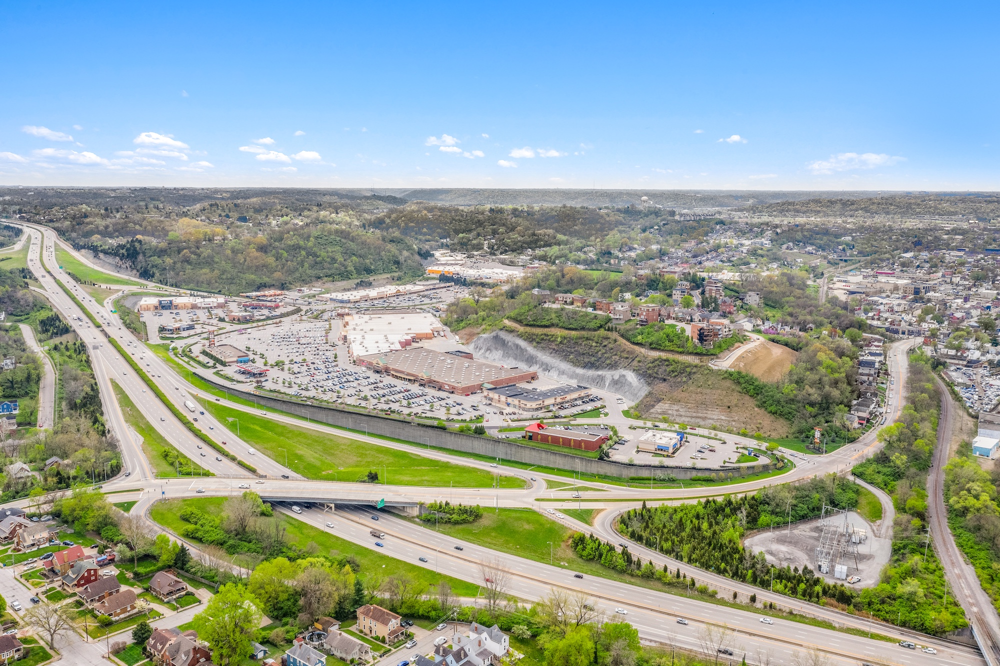 High-altitude aerial photograph of a shopping center showing highway interchange access and surrounding community