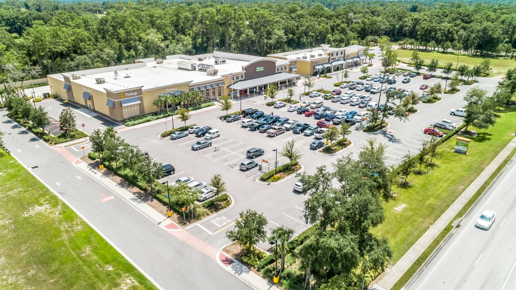 Aerial view of a grocery-anchored neighborhood shopping center with parking field and inline tenants