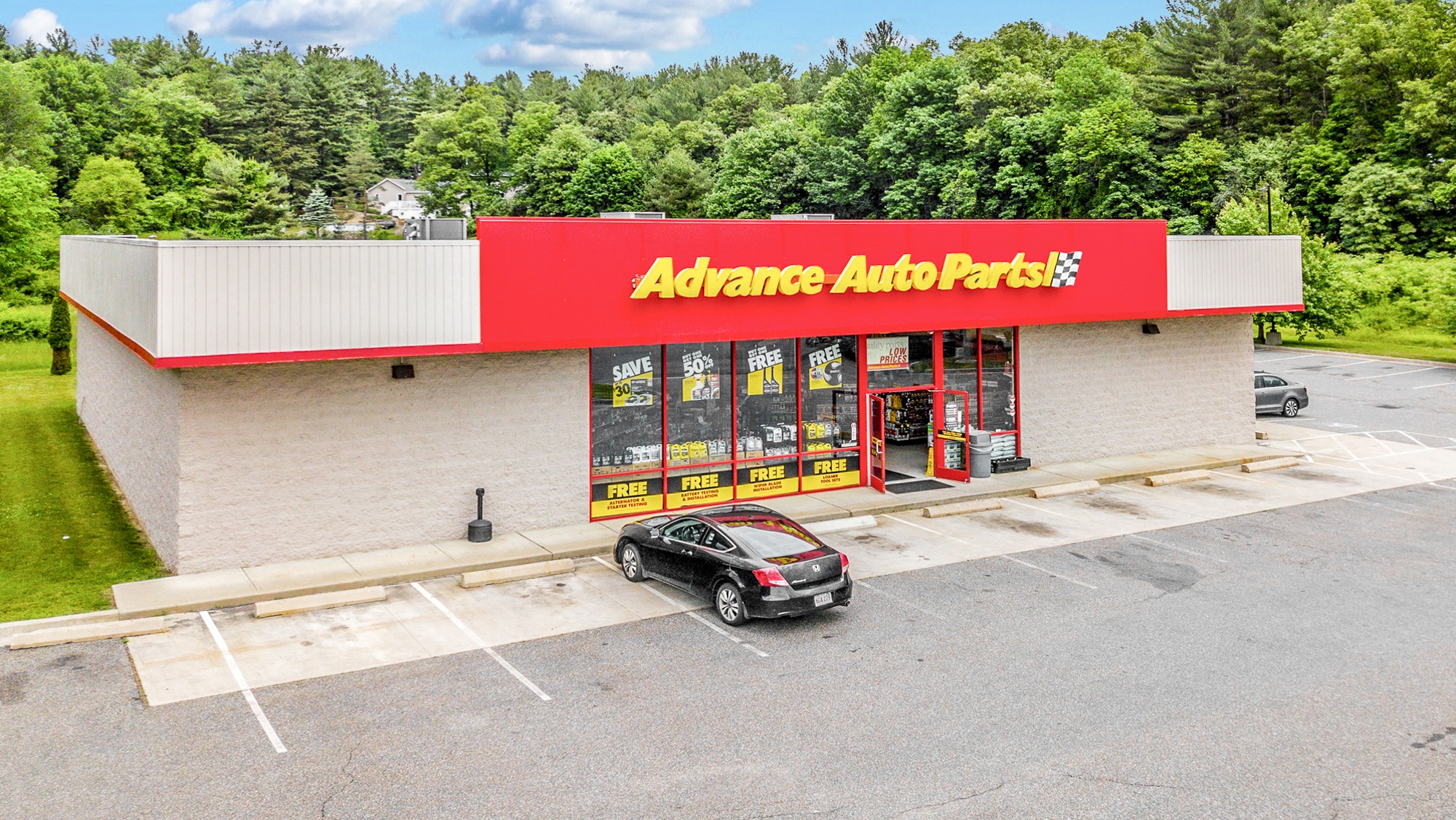 Low-altitude aerial of an Advance Auto Parts store showing building facade, entrance, and parking lot