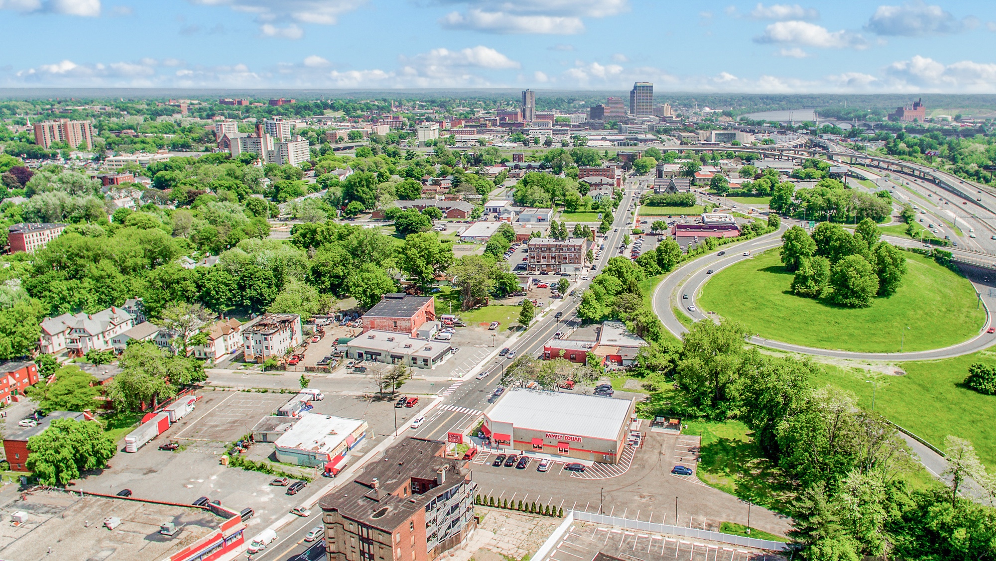 High-altitude aerial of a single-tenant dollar store showing parking field, highway access, and surrounding community