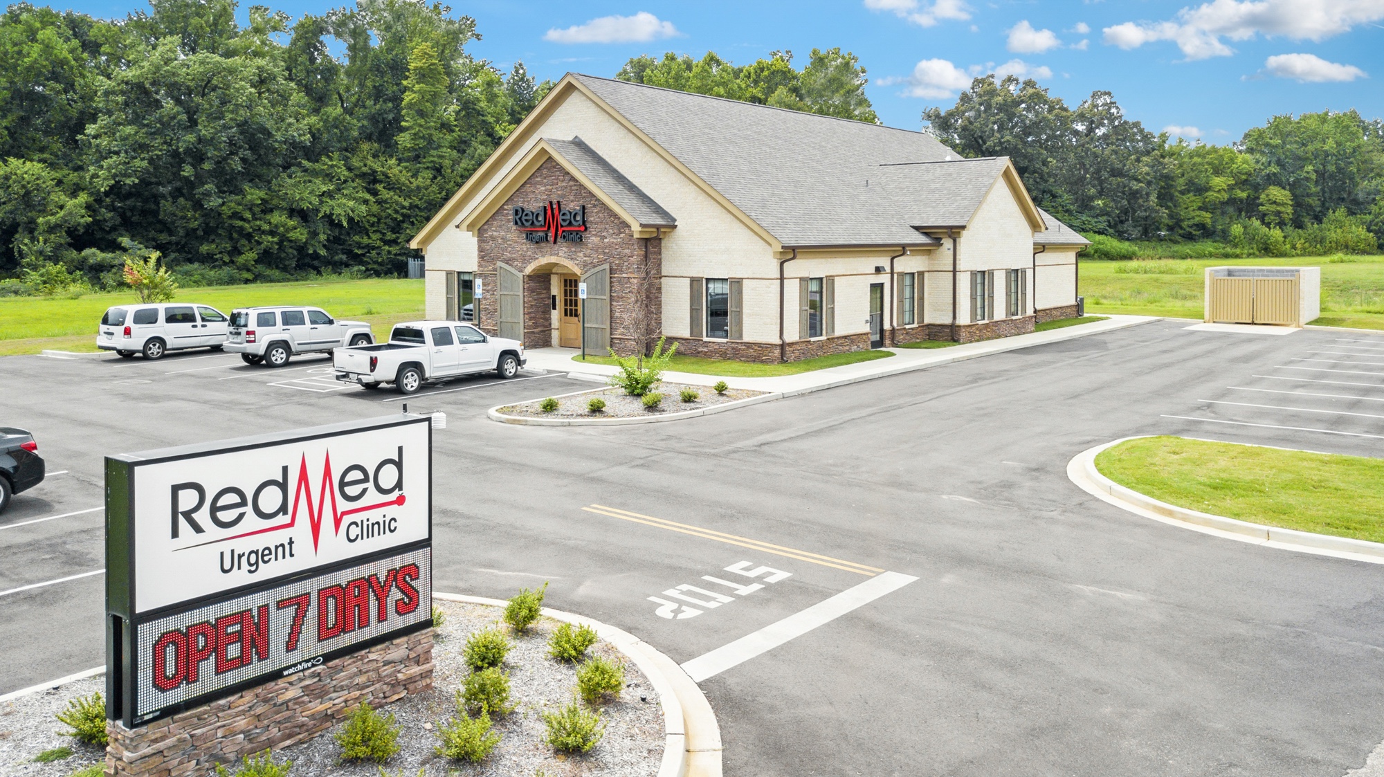 Aerial photograph of an urgent care clinic showing monument signage, patient entrance, and parking lot
