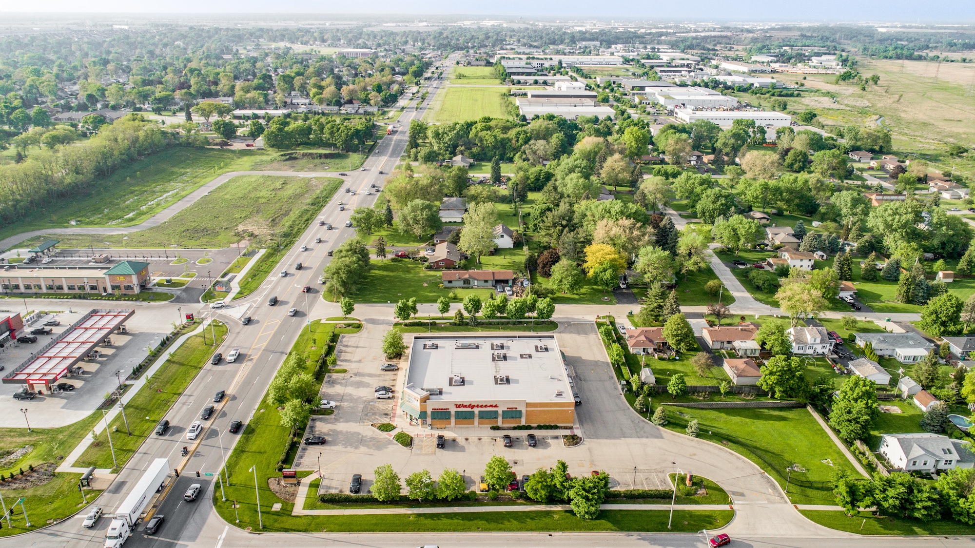 High-altitude aerial of a single-tenant pharmacy property showing full site, road frontage, and surrounding neighborhood