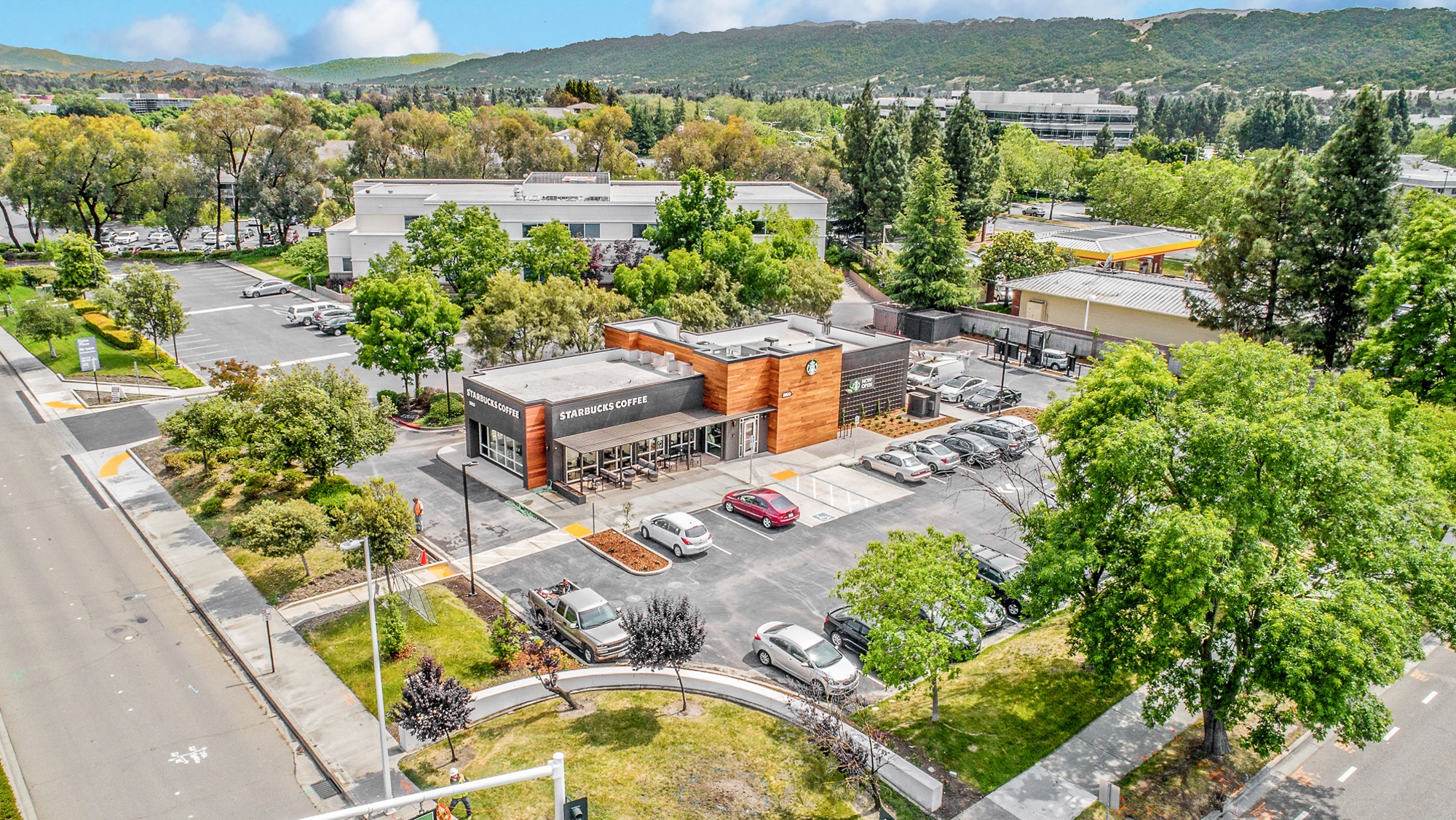 Aerial view of a single-tenant QSR restaurant with drive-through lane, parking, and surrounding retail context