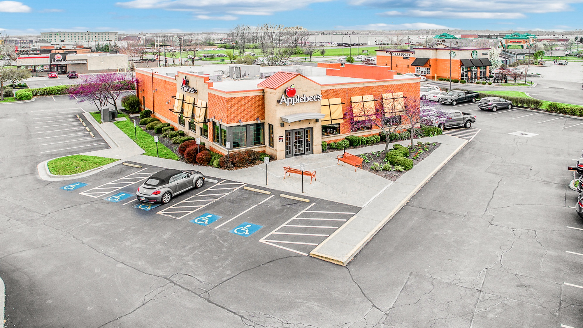 Aerial photograph of a freestanding restaurant building showing all sides, parking field, and surrounding retail