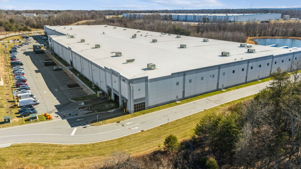 Aerial drone photography of flex industrial warehouse with rooftop HVAC units and employee parking