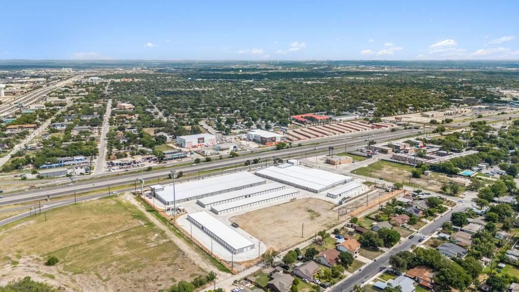 Wide aerial view of industrial storage facility complex along highway corridor