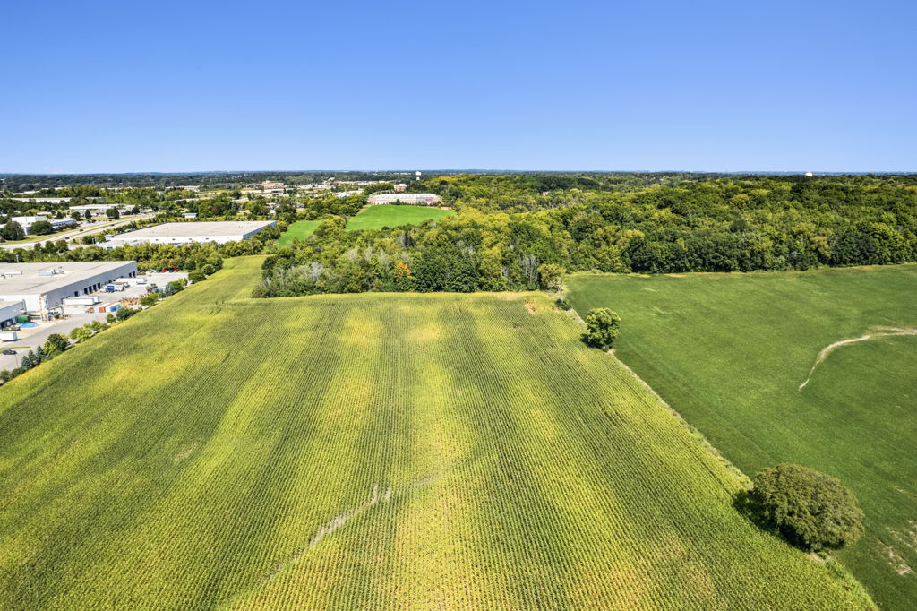 Aerial drone photography of agricultural cropland parcel adjacent to industrial development