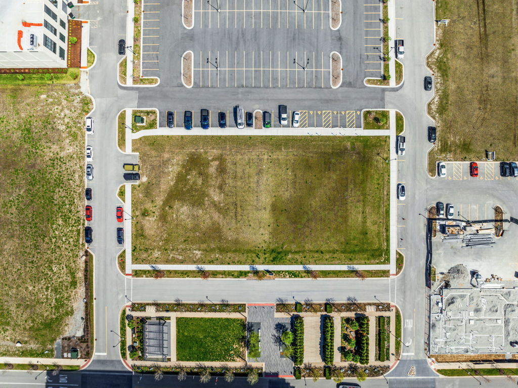 Eagle eye aerial view of vacant commercial development pad site with adjacent parking lot