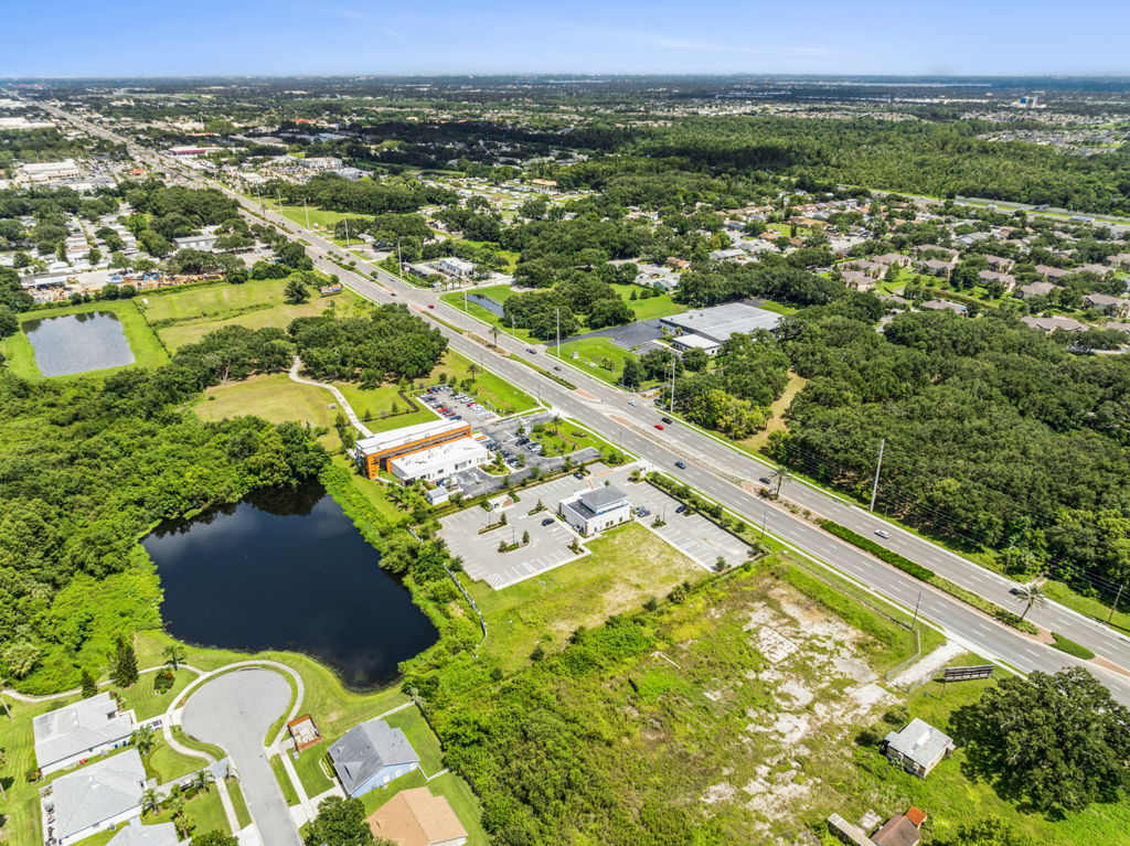 Aerial drone photography of commercial land parcel along major highway with surrounding residential development