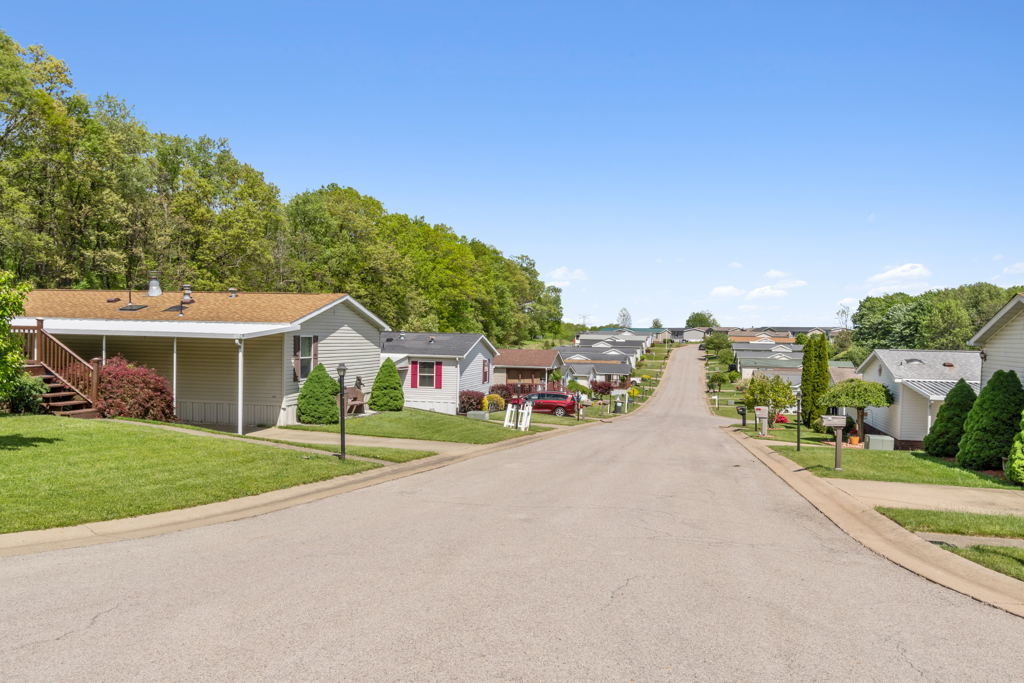 Ground-level photography of well-maintained suburban mobile home community street with landscaped yards