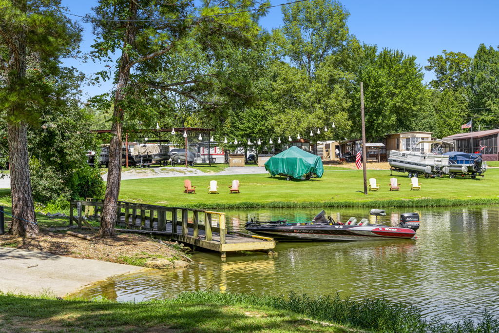 Ground-level photography of mobile home community waterfront amenity area with boat dock and seating