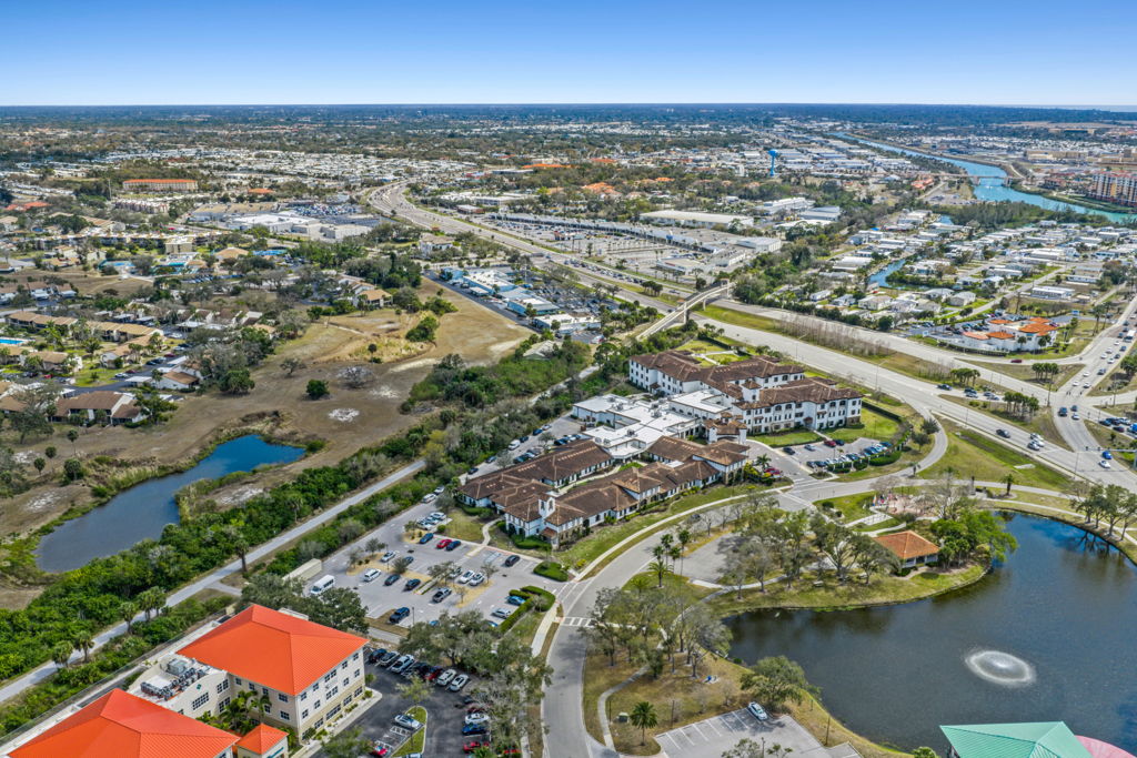 High-altitude aerial view of coastal apartment community with lake and highway access