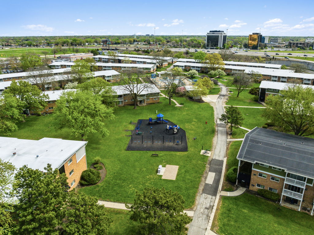 Aerial drone photography of garden-style apartment community with playground and green courtyard