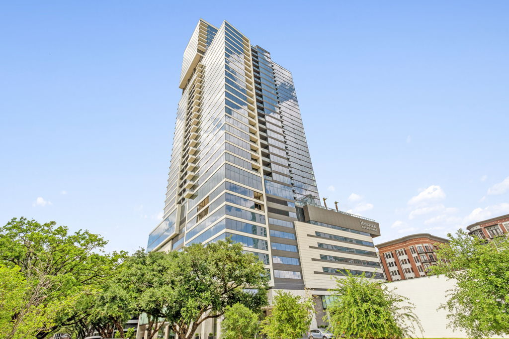 Ground-level photography of luxury high-rise apartment tower with glass facade in urban setting
