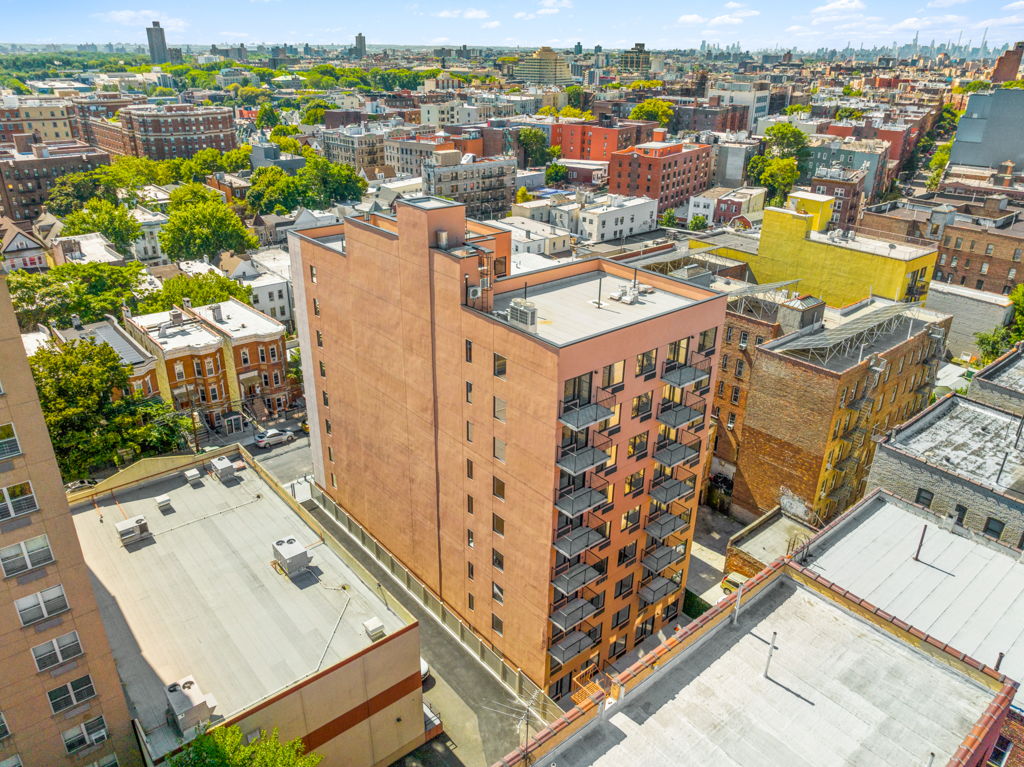 Aerial drone photography of urban mid-rise apartment building with balconies in dense neighborhood