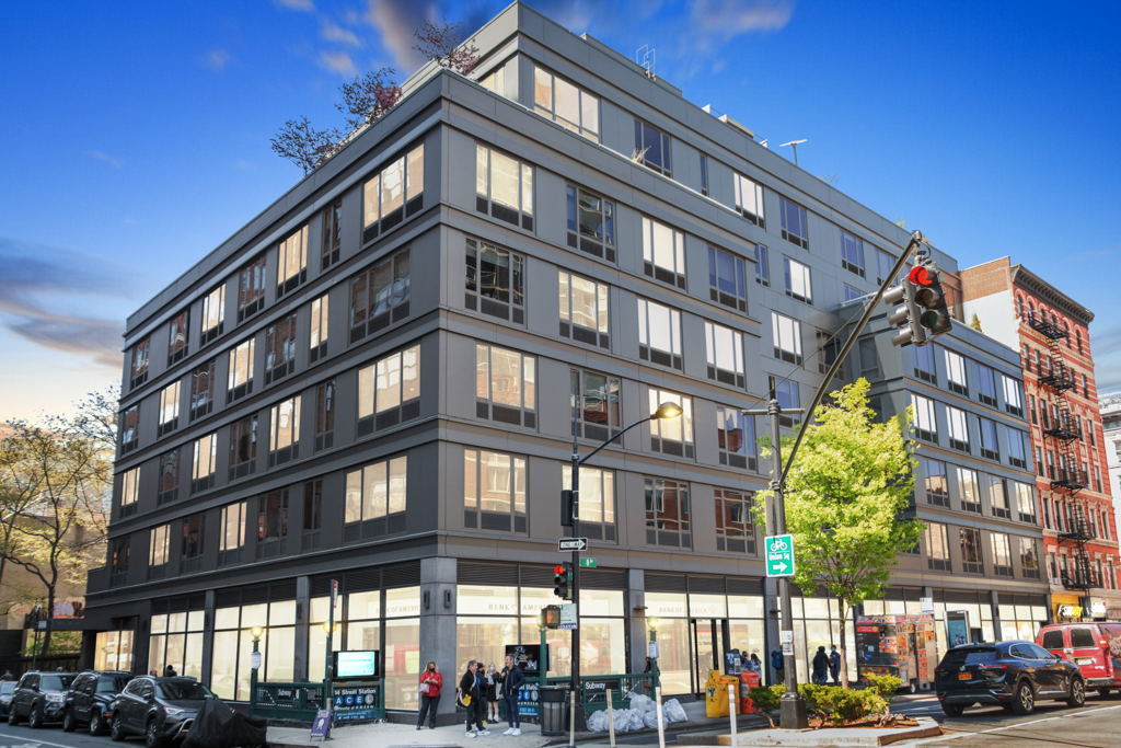Ground-level photography of urban mid-rise apartment building with ground-floor retail in New York City