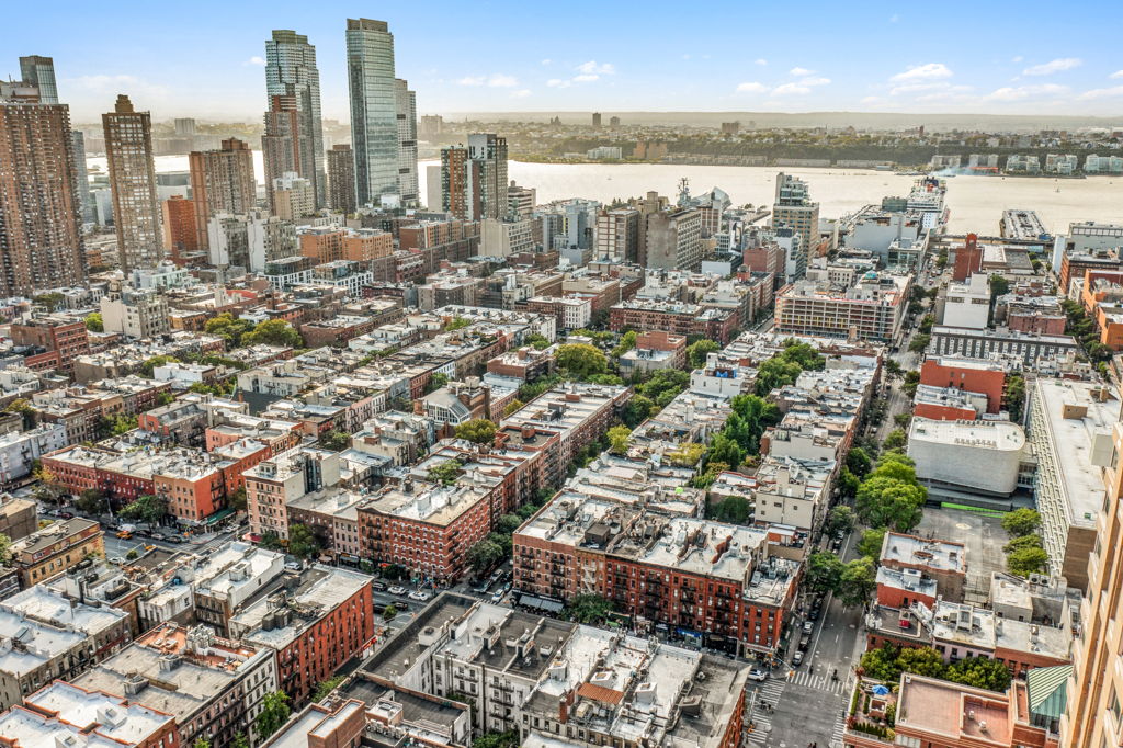 High-altitude aerial drone photography of dense urban residential neighborhood with Manhattan skyline