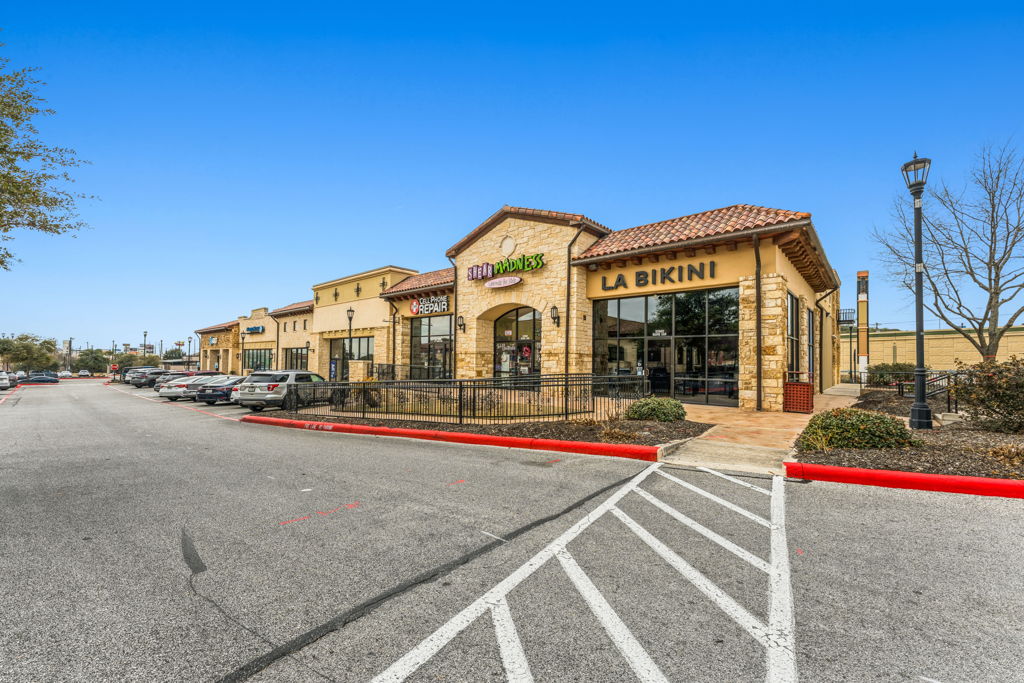 Ground-level photography of Mediterranean-style multi-tenant inline retail center with stone facade