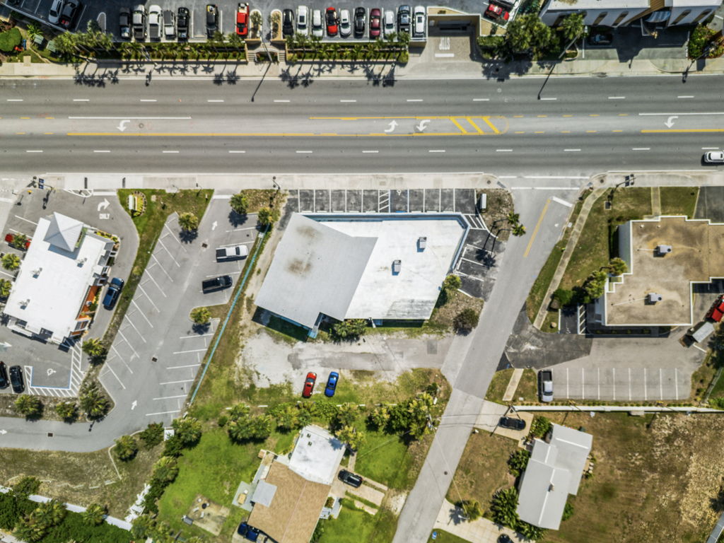 Ground-level photography of neighborhood multi-tenant retail center with storefront signage and parking