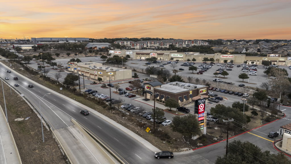 Twilight aerial drone photography of multi-tenant retail center with national tenants along highway