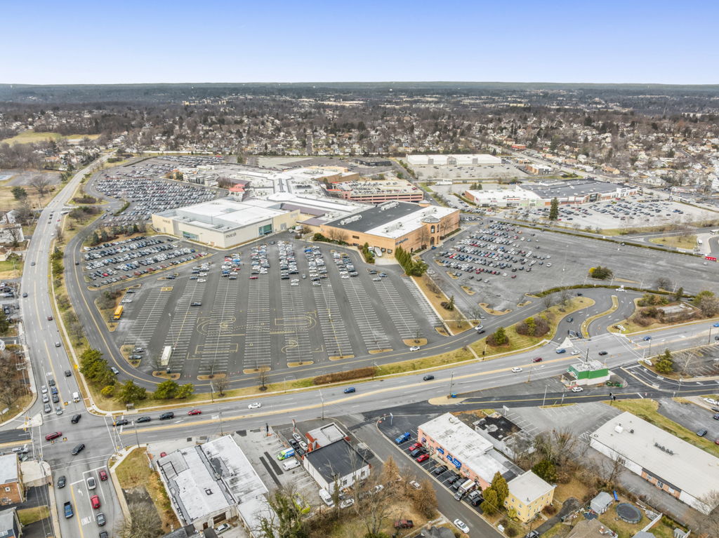 Wide aerial view of large multi-tenant shopping center with full parking field and surrounding retail