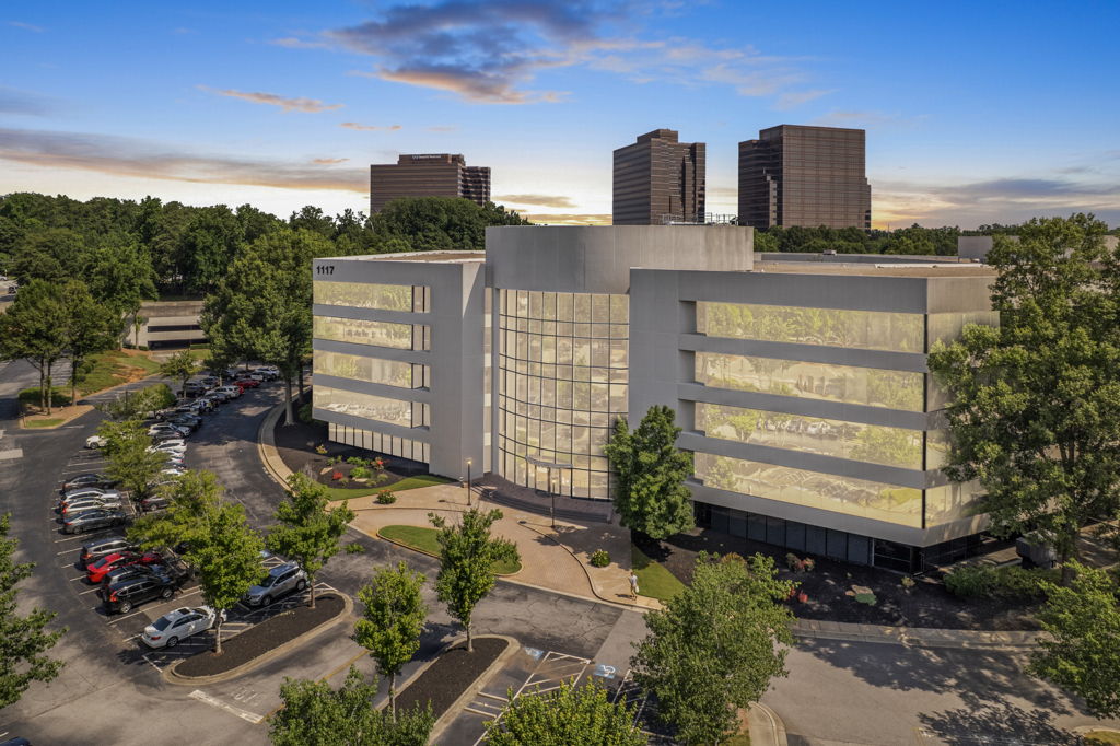 Twilight aerial drone photography of suburban office building in corporate campus with tree-lined parking