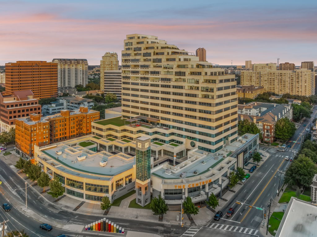 Twilight aerial drone photography of urban office high-rise tower in downtown mixed-use district
