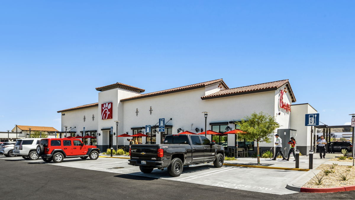 Ground-level photography of single-tenant QSR restaurant building with drive-through and outdoor patio seating