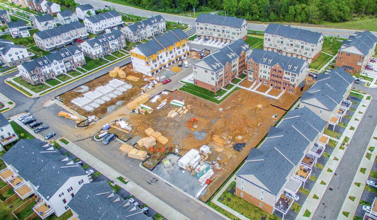 Aerial photography of a construction site showing building progress, equipment staging, and completed residential buildings