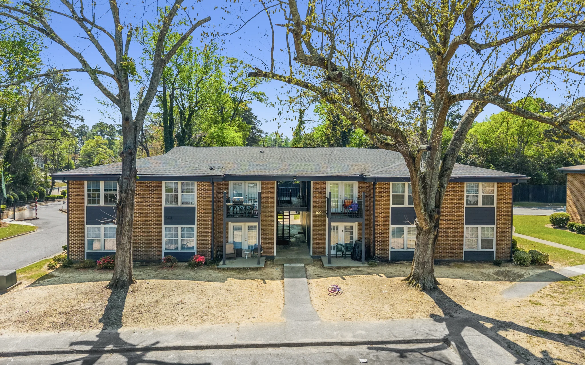 Two-story brick garden-style walk-up apartment building with French doors and balconies