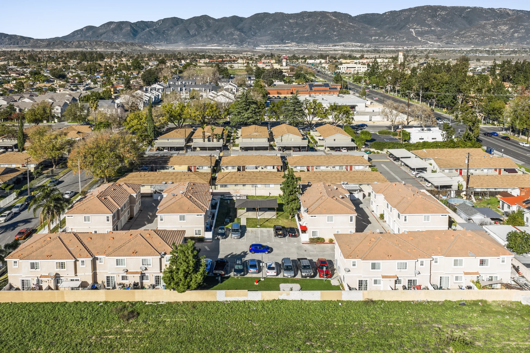 Aerial view of garden-style apartment complex with terra cotta tile roofs and mountain backdrop