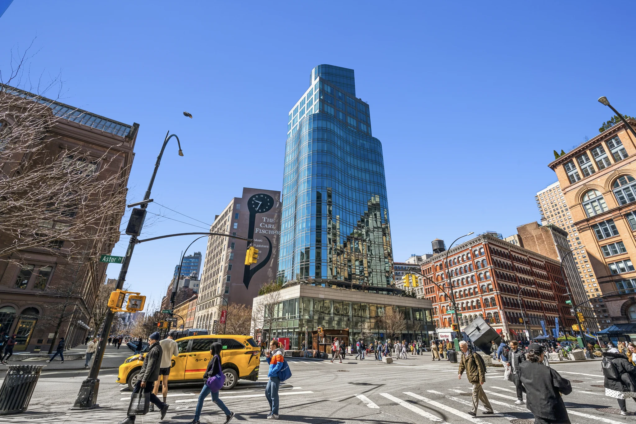 Modern glass-clad luxury high-rise apartment tower in dense urban Manhattan setting