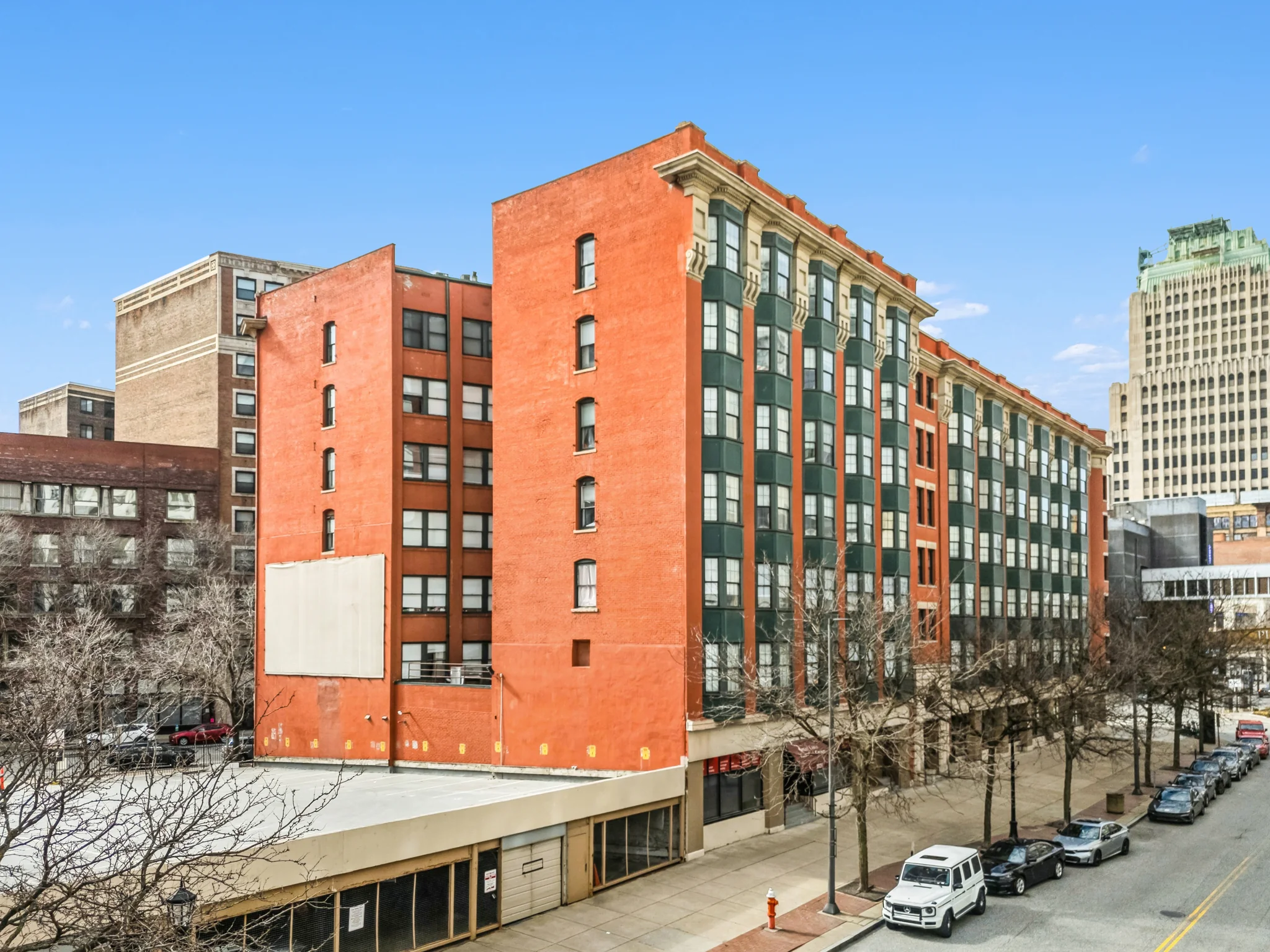Seven-story historic brick loft apartment building with green ornamental detailing in urban downtown