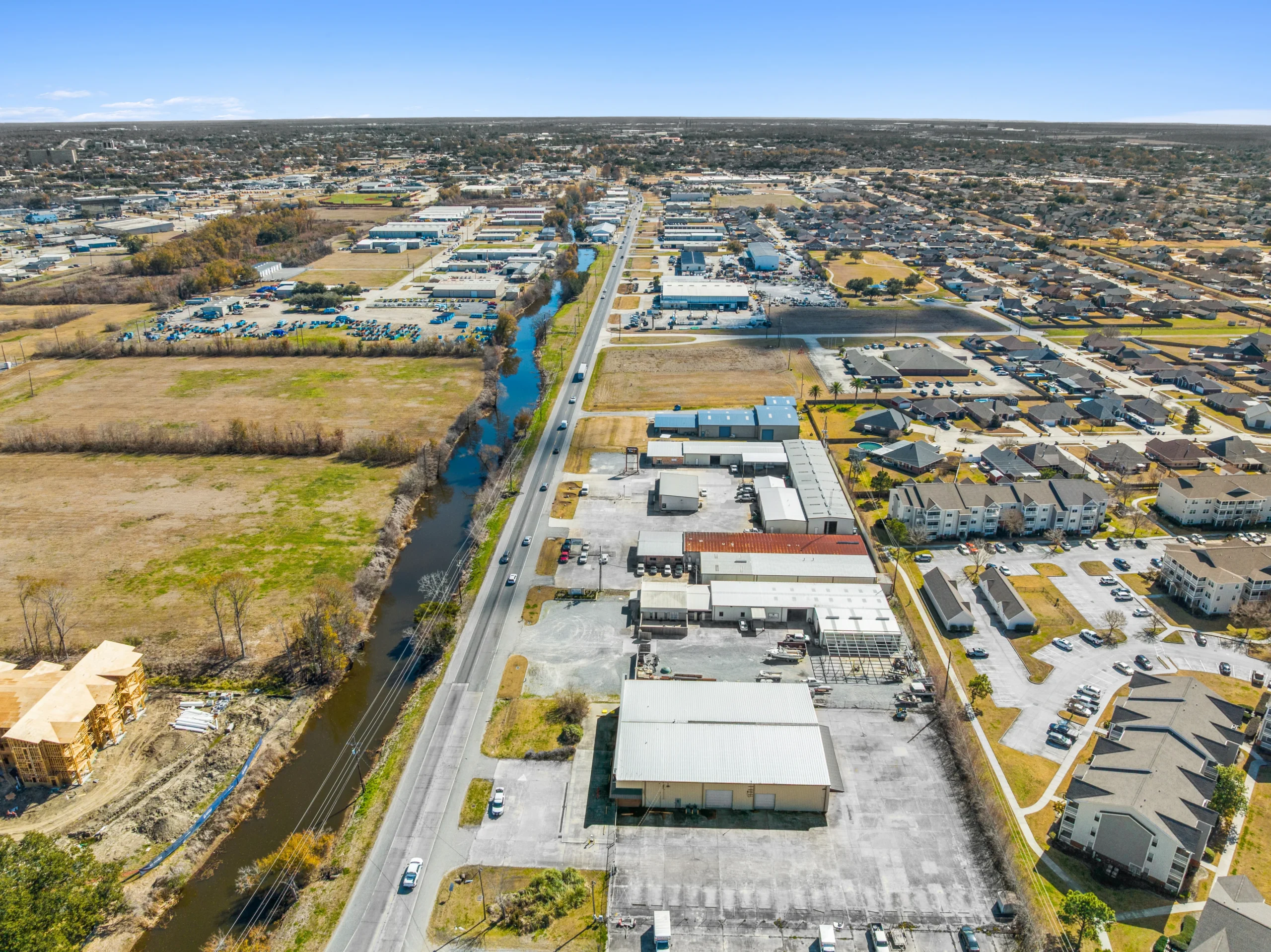 High-altitude aerial view of industrial corridor along canal with warehouse buildings