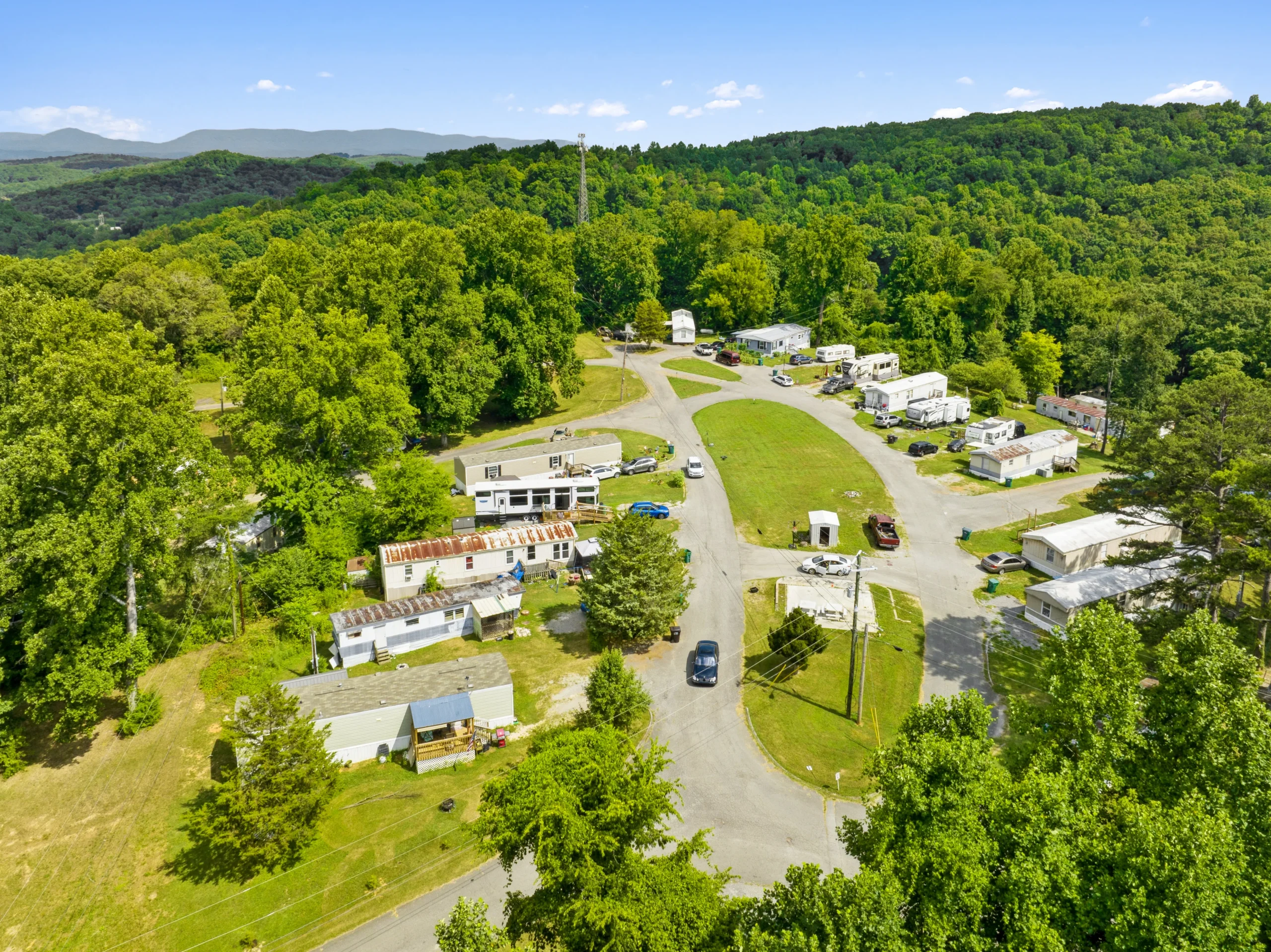 Aerial drone photography of small Appalachian mobile home community surrounded by forest and mountains