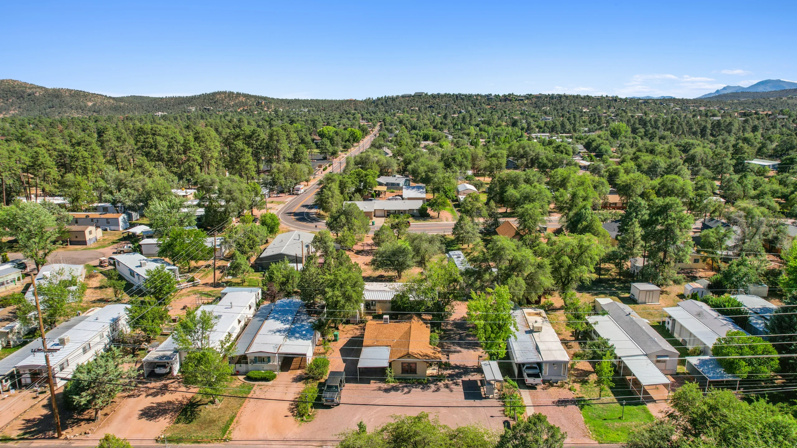 Aerial drone photography of mobile home community nestled among pine trees with mountain views