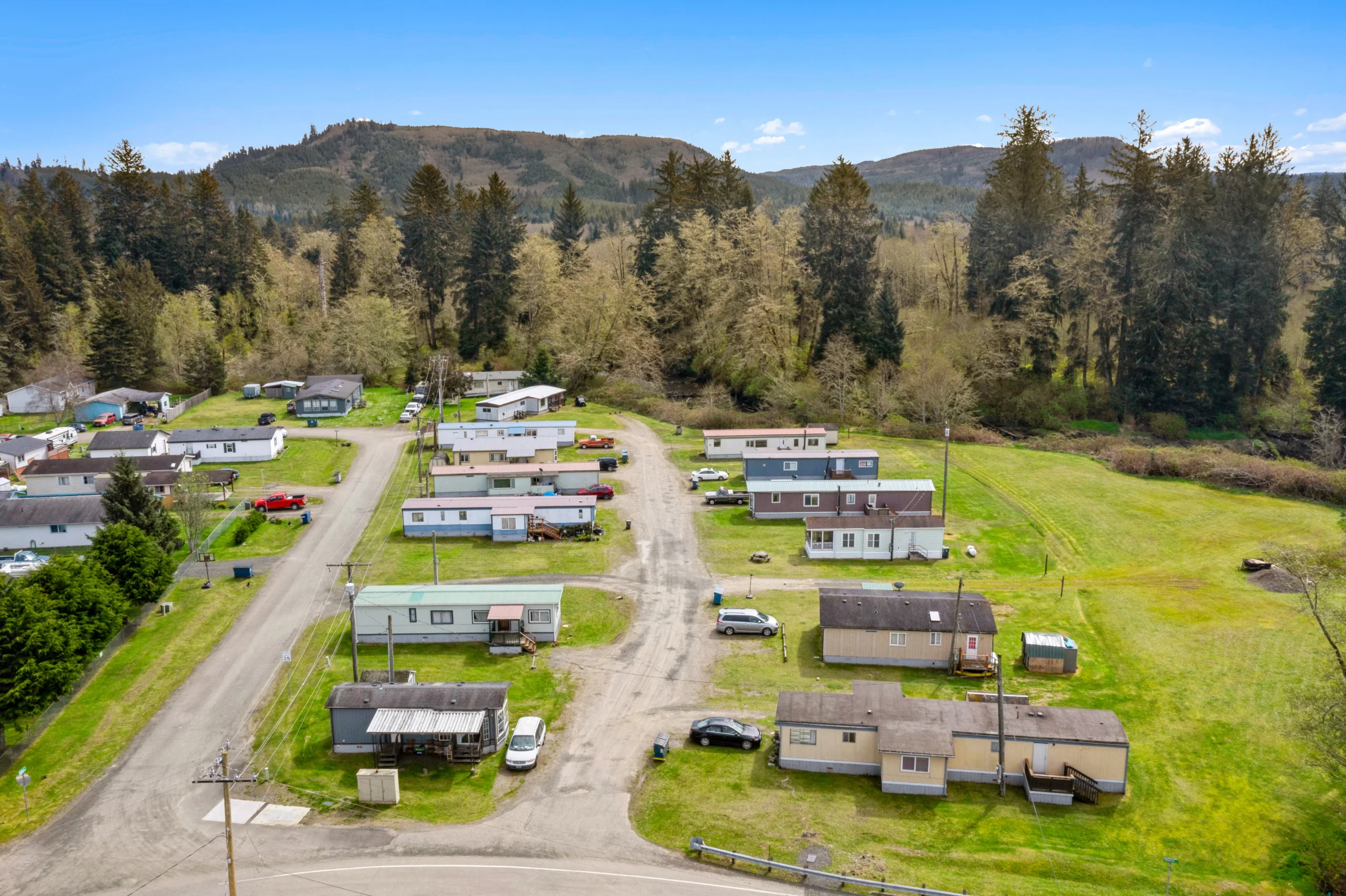 Aerial drone photography of mobile home community in mountain valley with forested hillside backdrop