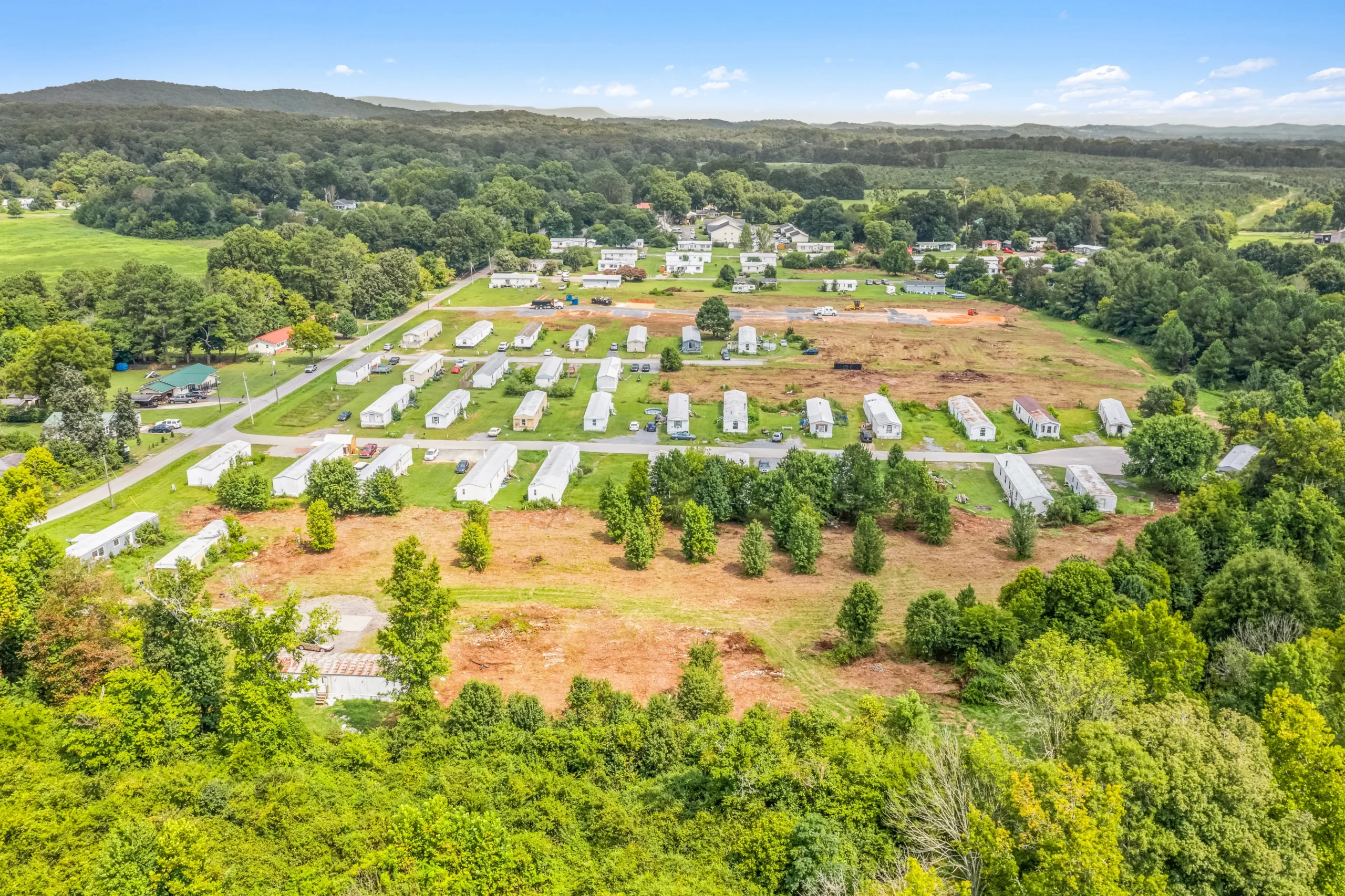 Aerial drone photography of rural mobile home community with expansion land and mountain backdrop