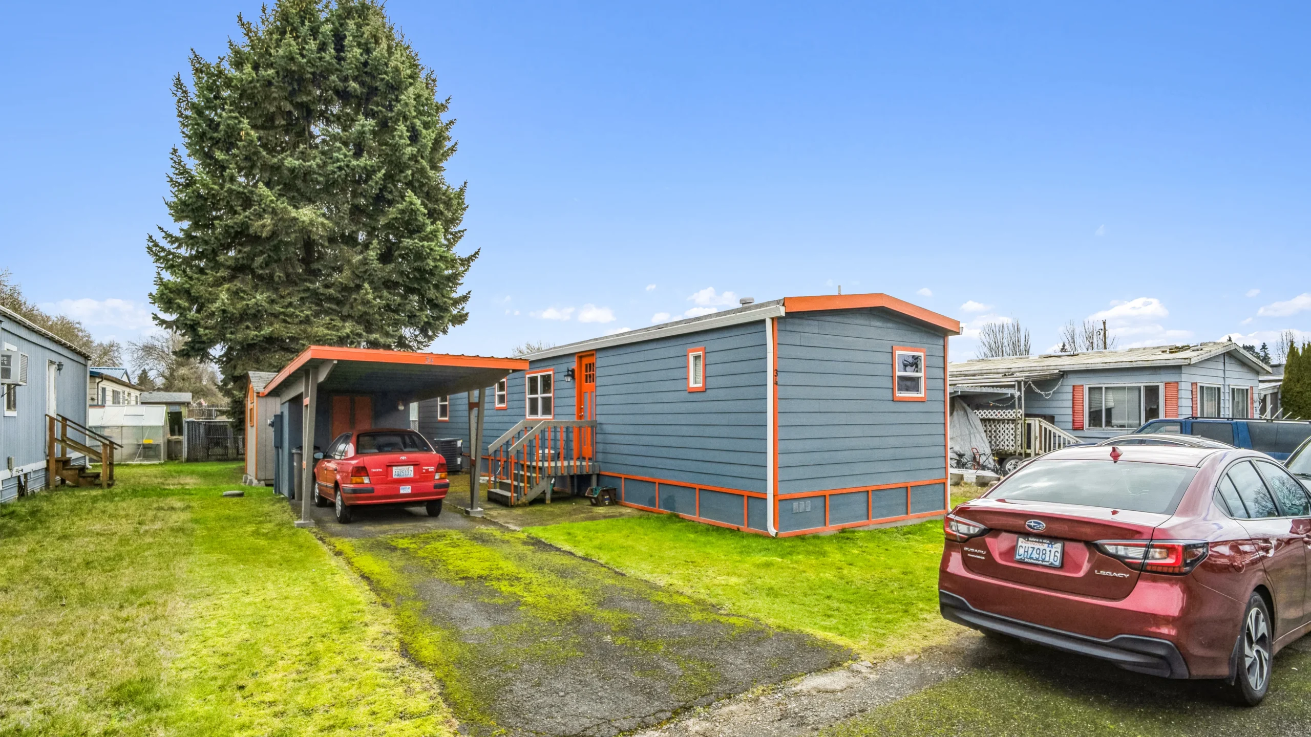 Ground-level photography of recently updated manufactured home with carport in community setting