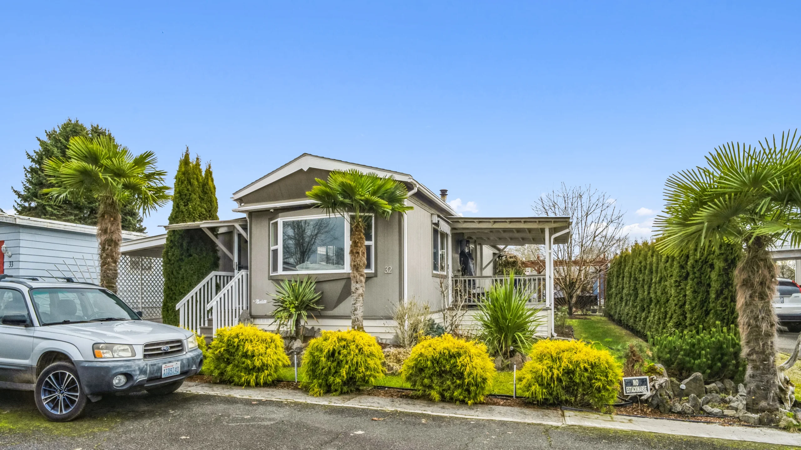 Ground-level photography of upscale manufactured home with palm tree landscaping and covered porch