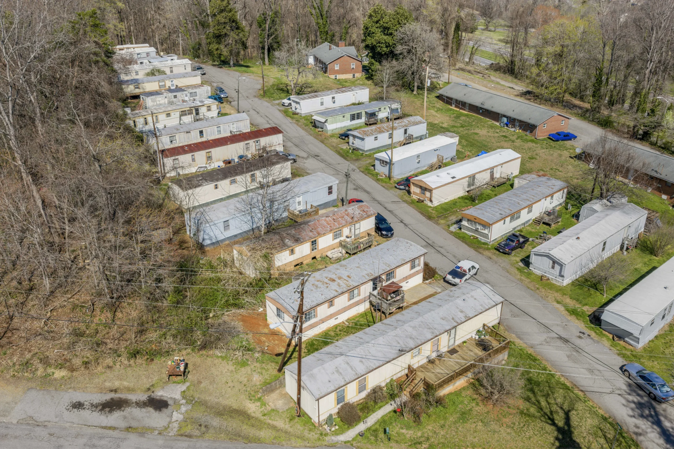 Aerial drone photography of value-add mobile home community with older units and surrounding woodland
