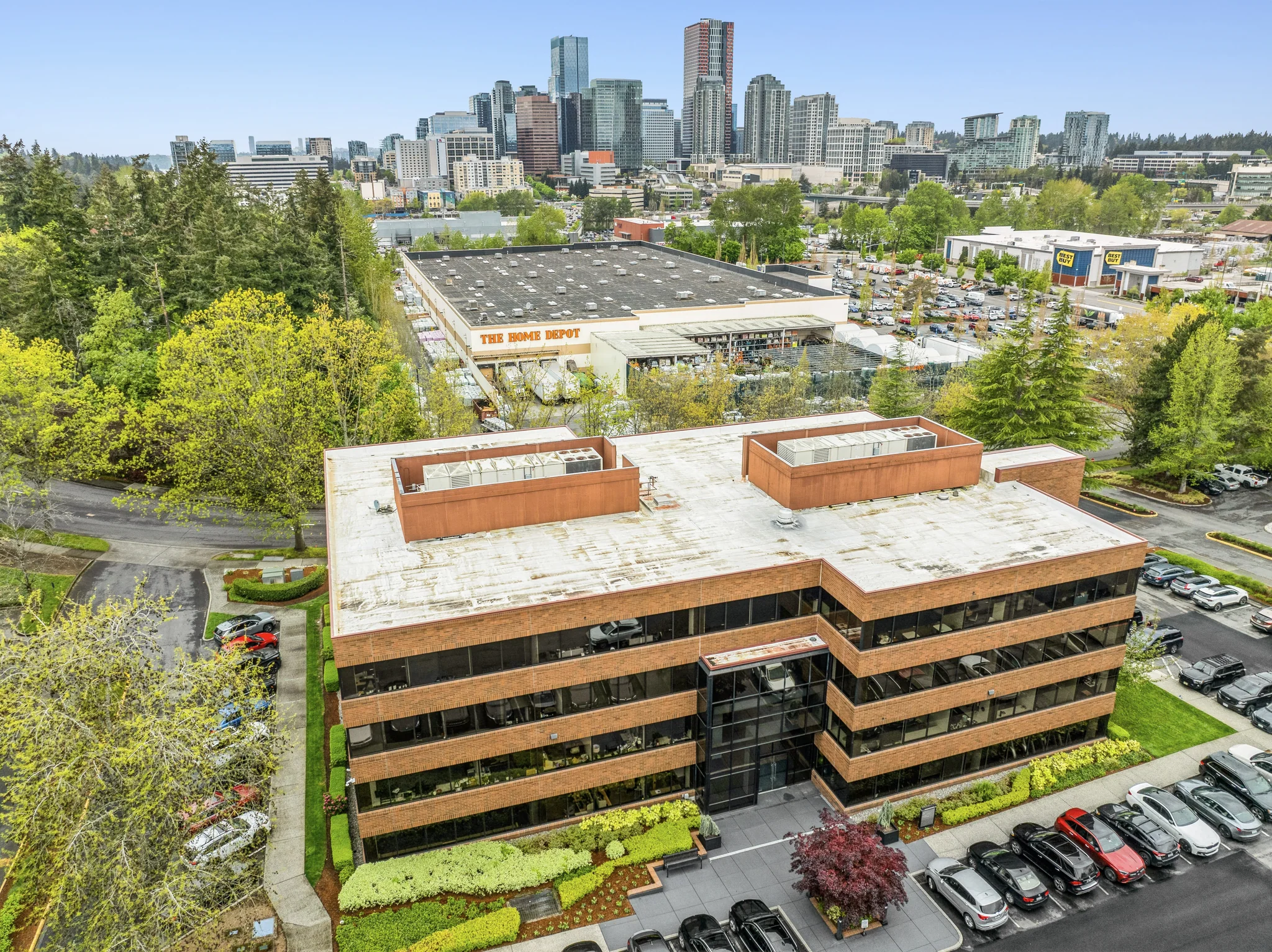 Mid-rise multi-tenant office building with brick facade and downtown skyline background