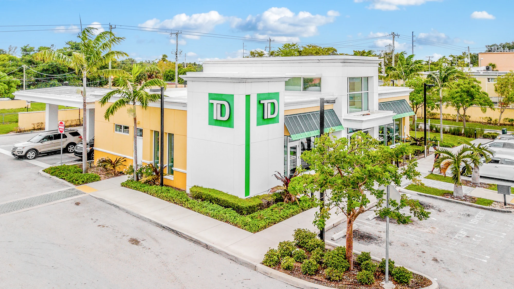 Aerial photograph of a single-tenant TD Bank branch with modern stucco architecture, drive-up canopy, branded green signage, and customer parking
