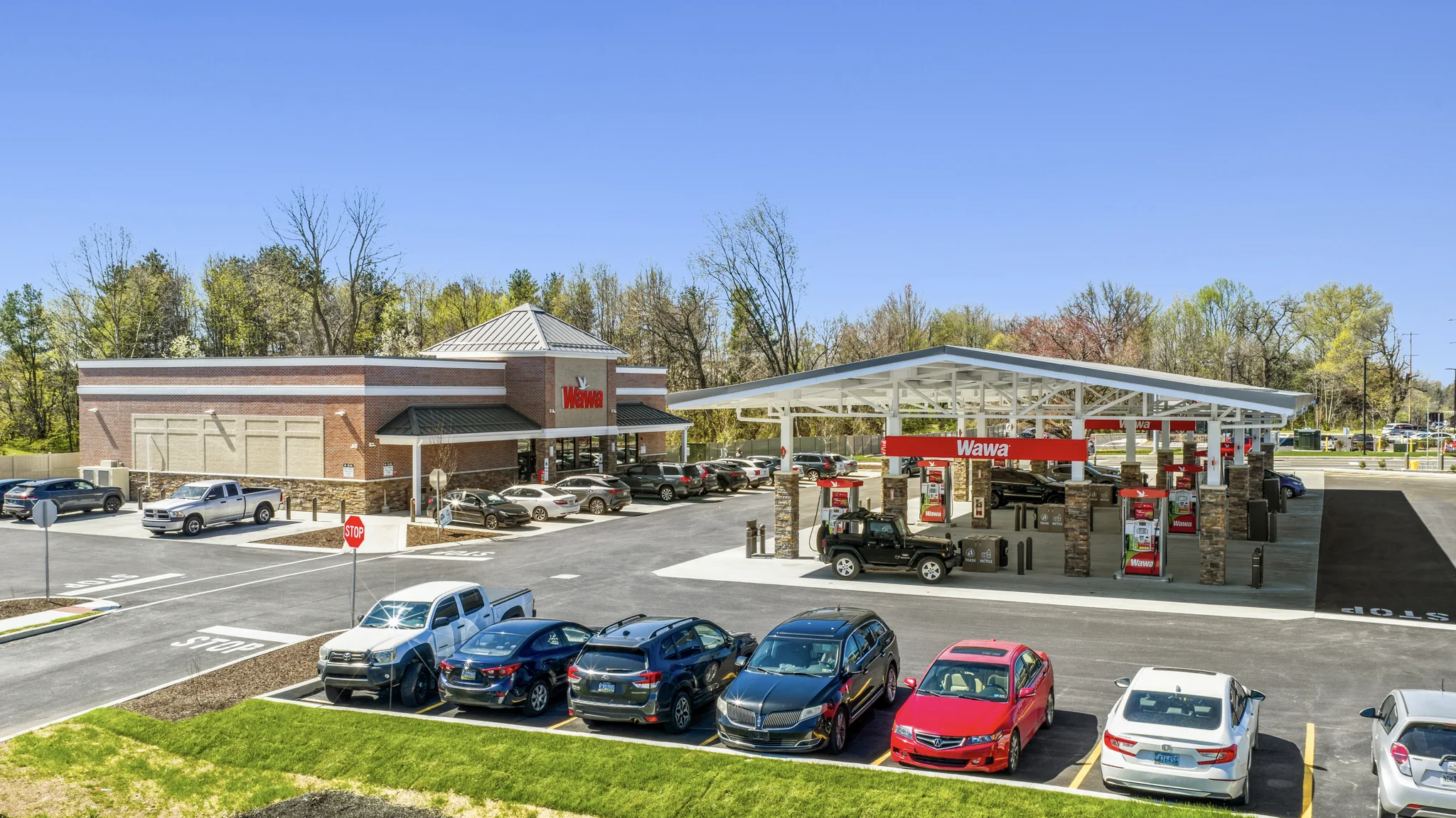 Aerial photograph of a single-tenant Wawa convenience store and gas station with fuel canopy, parking field, and trade area context