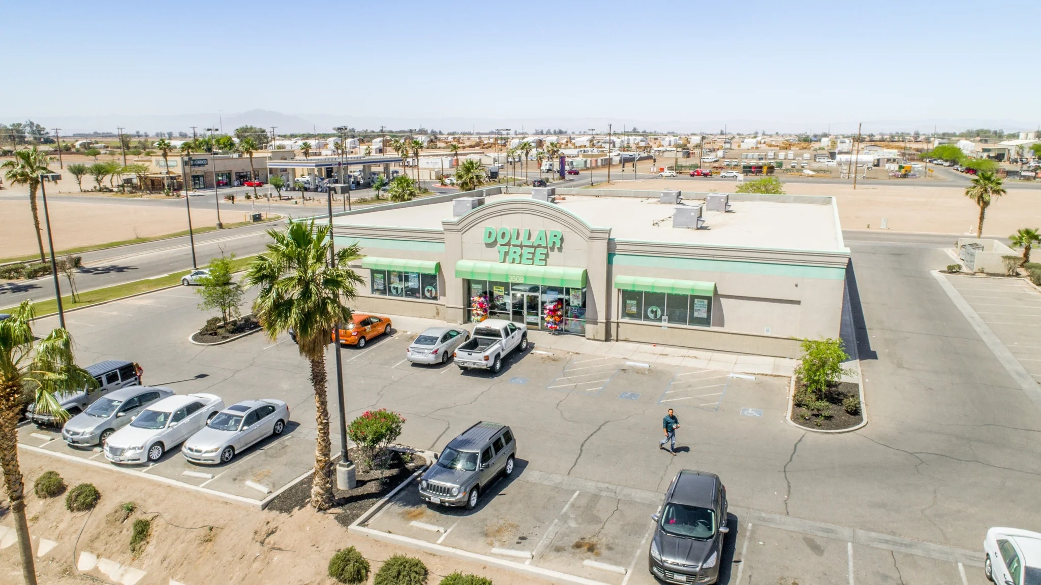 Aerial photograph of a single-tenant Dollar Tree discount store with prominent storefront facade, parking field, and surrounding trade area