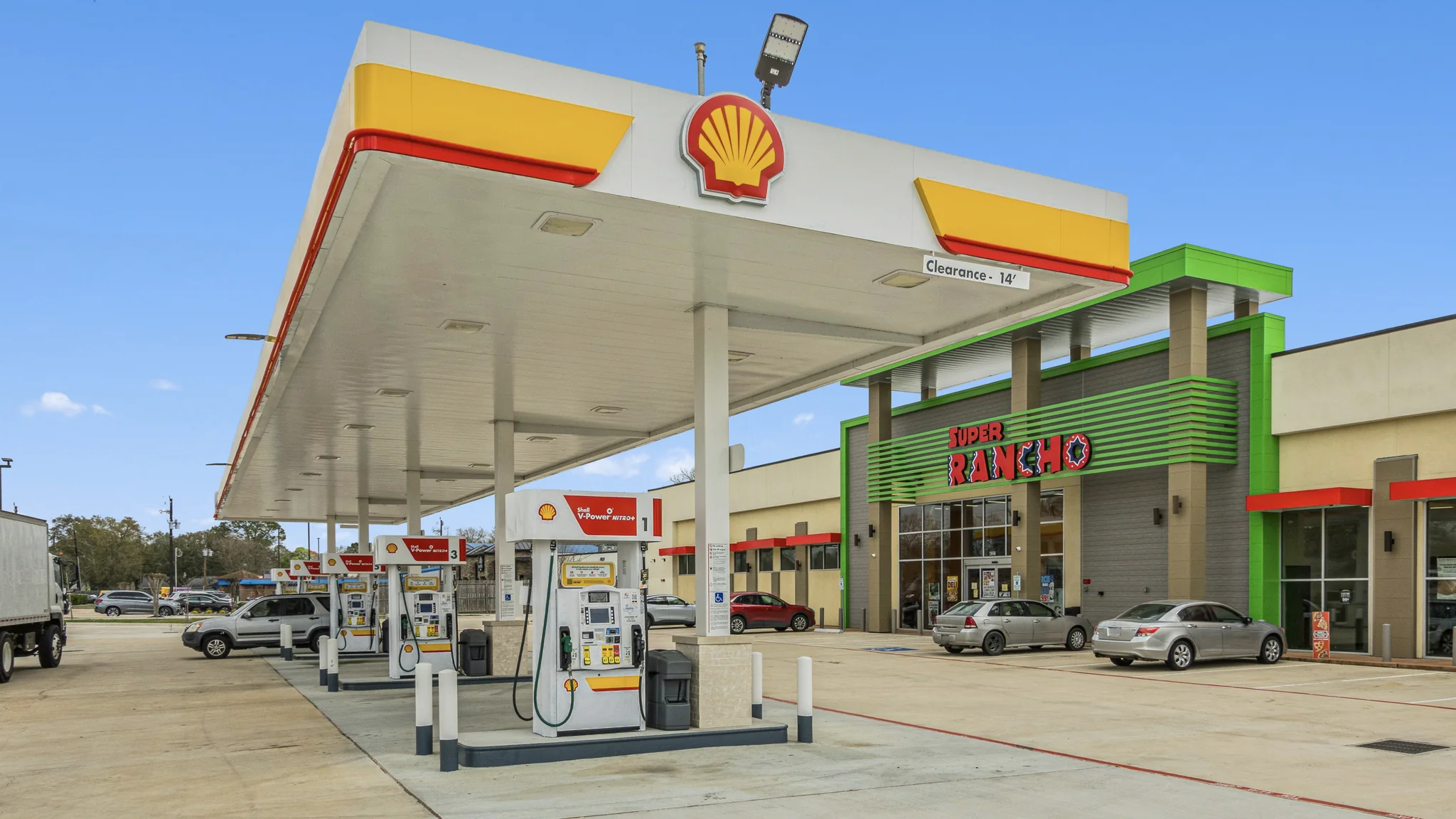 Ground-level photograph of a single-tenant Shell gas station with fuel canopy, dispensers, and adjacent convenience store storefront
