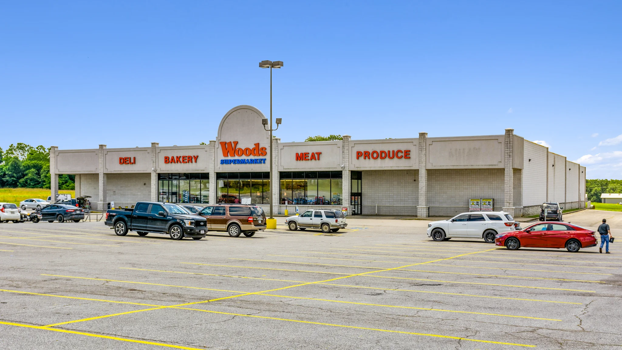 Low-altitude aerial of a single-tenant Food City grocery store anchor with attached pharmacy, cafe, and large customer parking field