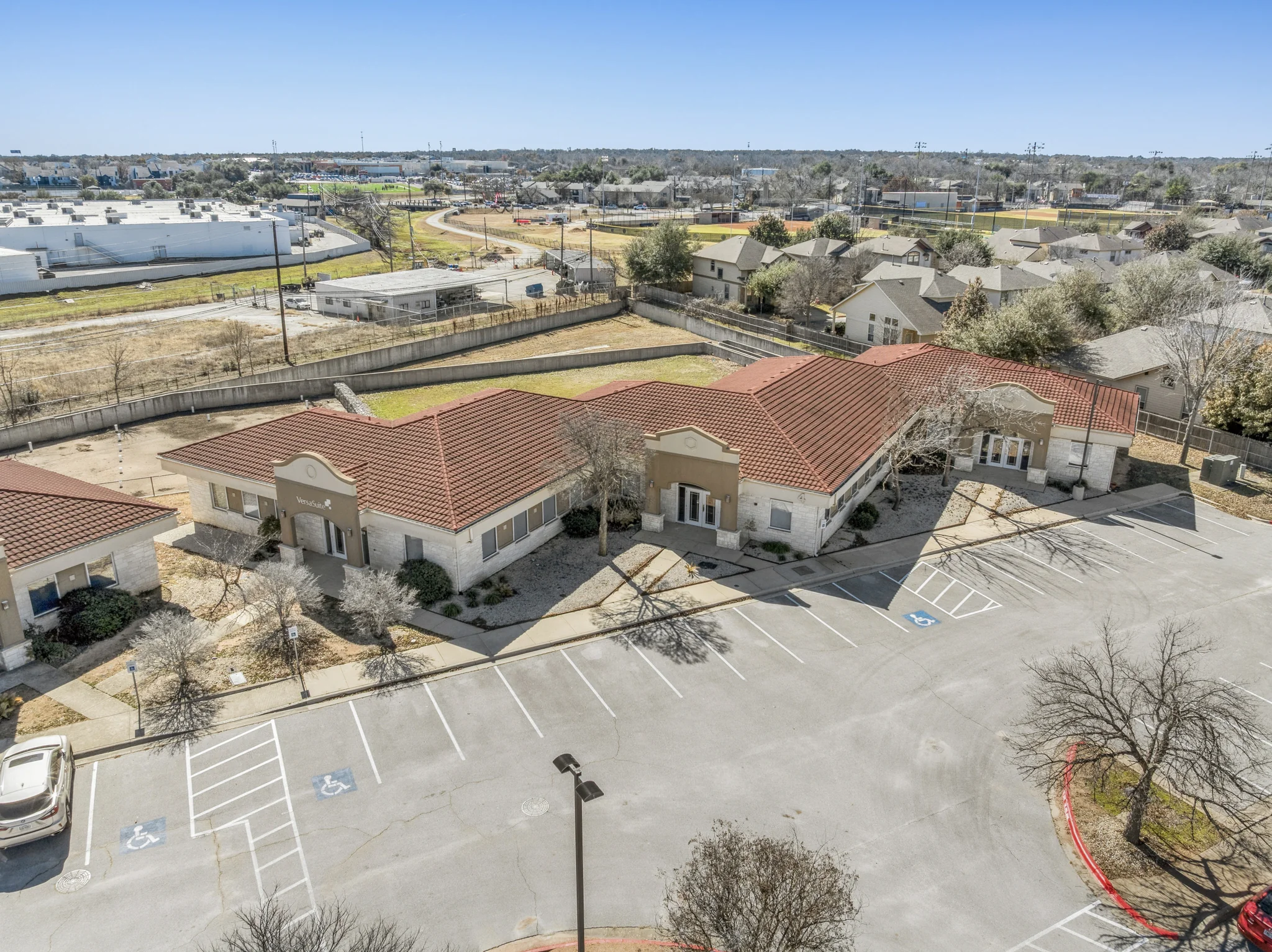 Aerial view of single-tenant office building with red tile roof and ample surface parking