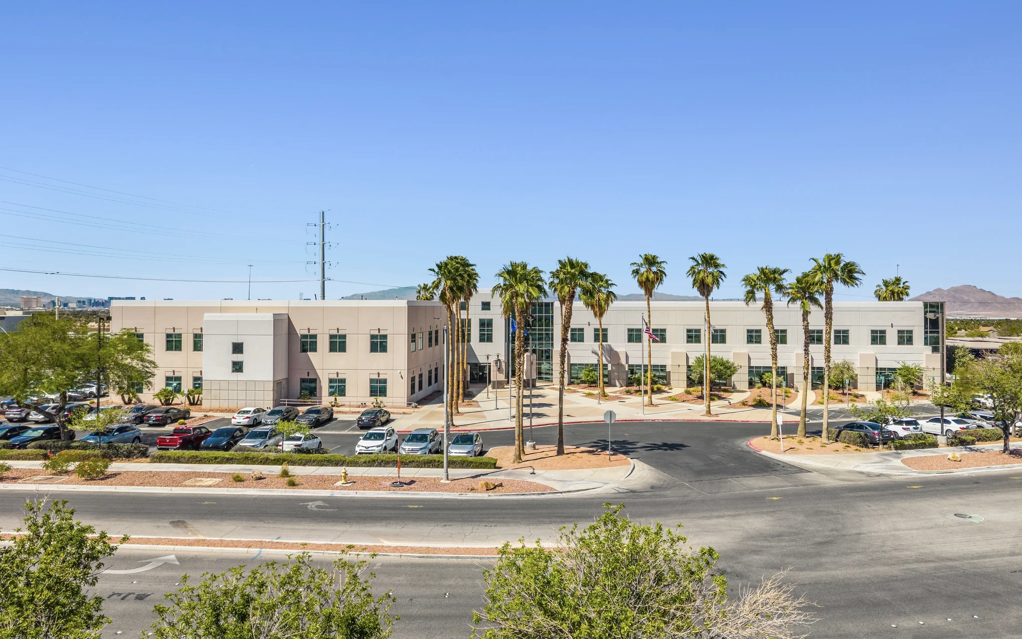 Two-story single-tenant corporate office building with palm trees and American flag